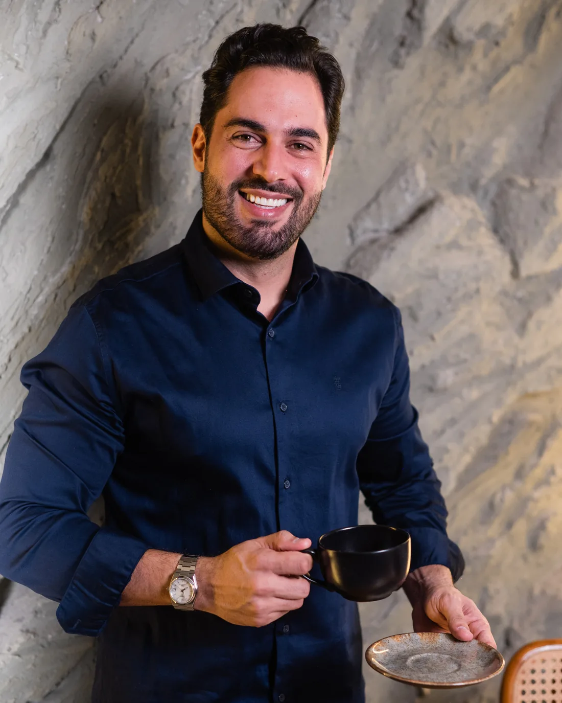 Augusto Caetano sorrindo, com uma xícara de café na mão